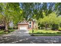 Traditional brick home on a tree-lined street featuring a spacious driveway and well-kept front yard at 1305 Foxfield Rd # 60, Waxhaw, NC 28173