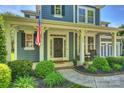 Inviting front porch with American flag, neatly landscaped yard, and rocking chairs at 1405 Ridge Haven Rd, Waxhaw, NC 28173