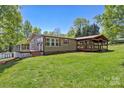 View of the house's covered deck and the yard behind the home at 2942 Denwood Dr, Claremont, NC 28610