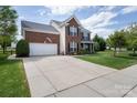 Attractive two-story home boasts a well-maintained lawn, wide driveway, and classic brick and siding exterior at 1002 Banaba Dr, Indian Trail, NC 28079