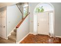 Bright foyer featuring wood floors and a staircase with a large arched window above door at 11024 Hunters Trace None, Charlotte, NC 28262