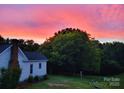 Lovely sunset view of a charming home surrounded by large green trees, creating a peaceful and private setting at 1165 Old Salisbury Concord Rd, Concord, NC 28025