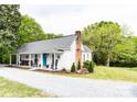 Beautiful exterior view of home with rocking chairs on the porch, a brick chimney, and a lush, landscaped yard with scattered trees at 1165 Old Salisbury Concord Rd, Concord, NC 28025