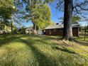 Expansive backyard with lush green grass, mature trees, and the rear exterior of the brick home with carport at 1218 Forestdale Dr, Salisbury, NC 28144