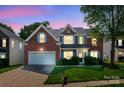 Beautiful brick home with bright blue shutters, a well-manicured lawn, and attached two-car garage at dusk at 12404 Mcallister Park Dr, Charlotte, NC 28277