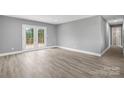 Bright living room with modern wood flooring, fresh gray paint, and french doors to a back porch at 2019 Kingston Rd, Kingstown, NC 28150