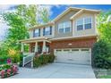 Beautifully designed home featuring a brick facade, a two-car garage, and a charming front porch with lush landscaping at 2202 Chickasaw Loop, Rock Hill, SC 29732