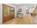 Bright foyer showcasing hardwood floors, double doors, and a decorative table beneath a circular mirror at 2411 Ainsdale Rd, Charlotte, NC 28226