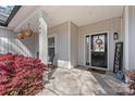 Inviting covered front porch with decorative plants and a welcoming black front door with sidelights at 247 Timberland Loop, Mooresville, NC 28115