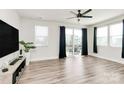Sunlit living room featuring hardwood floors, sliding glass doors to a balcony, and a modern ceiling fan at 2520 Ensemble Ct, Charlotte, NC 28262