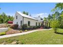 Scenic shot of a white farmhouse with black trim, complemented by lush landscaping and a red barn in the background at 29268 Pennington Rd, Albemarle, NC 28001