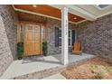 Inviting front porch features a wooden door, chair, and decorative plants creating a cozy entrance at 3013 Isle Ln, Monroe, NC 28110
