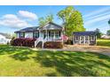 A well-maintained home featuring a charming front porch, landscaped lawn, and a shed in the background at 303 Caroline Ave, Lowell, NC 28098