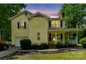 Charming two-story yellow home featuring a covered front porch and attached garage, with evening lighting at 3619 Baywoods Ct, Gastonia, NC 28056