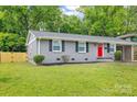 A well-maintained single-story home features a gray exterior, black shutters, and a vibrant red front door at 4009 Dunwoody Dr, Charlotte, NC 28215