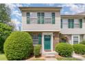 Inviting townhome with green door and shutters, set amidst lush landscaping and charming brick accents at 513 Lex Dr, Charlotte, NC 28262