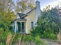 Home exterior view with overgrown lawn, mature shrubs and partially glass enclosed porch at 6000 S Main St, Salisbury, NC 28147