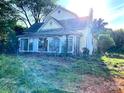 View of a two-story home with a sunroom surrounded by overgrown greenery at 6000 S Main St, Salisbury, NC 28147