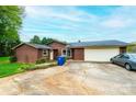 A single-story home has brown siding, a large driveway and an attached garage, offering both practicality and charm at 1025 Hefner Nw Dr, Conover, NC 28613