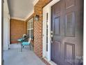 Inviting front porch with a stylish dark-brown front door, brick accents, and a cozy seating area for relaxing at 105 Runningdeer Dr, Mooresville, NC 28117