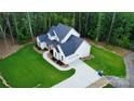 An aerial of the white two-story home with landscaped yard and long driveway at 1123 Fern Hill Rd, Mooresville, NC 28117