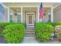 Inviting front porch with decorative columns, blooming flowers, American flag and manicured greenery at 1151 Donelea Nw Ln, Concord, NC 28027