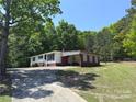 Charming single-story home with a brick foundation, white siding, and a winding driveway surrounded by lush trees at 12719 Cottonville Rd, Norwood, NC 28128