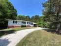 Inviting single-story home with a long driveway, surrounded by mature trees and a well-maintained lawn at 12719 Cottonville Rd, Norwood, NC 28128