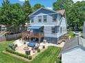 Aerial view showcases a blue two-story home with a deck, patio, firepit, and landscaped yard at 1421 Lyon Ct, Charlotte, NC 28205