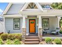 Inviting home exterior with stone pillar bases, an orange door, and a cozy seating area on the porch at 1421 Lyon Ct, Charlotte, NC 28205