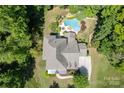 Aerial view of a home with a lush, landscaped backyard including a custom-shaped pool and mature trees at 2153 Darian Way, Waxhaw, NC 28173