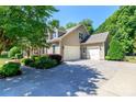 Spacious three-car garage connected to a charming two-story home, surrounded by mature trees and manicured landscaping at 2153 Darian Way, Waxhaw, NC 28173