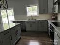 Modern kitchen with gray cabinets, stainless steel appliances, granite countertops, and a breakfast bar area at 6518 Blackwood Ln, Waxhaw, NC 28173