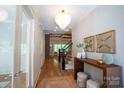 Inviting hallway with hardwood floors, elegant light fixture, console table, and staircase to the upper level at 724 Ideal Way, Charlotte, NC 28203