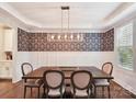 Elegant dining room with decorative wallpaper, wainscoting, modern chandelier, and hardwood floors at 7809 Greenfield Dr, Charlotte, NC 28270