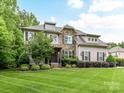 Beautiful two-story home showcasing stone accents, dormer windows, professional landscaping, and a well-manicured front lawn at 7809 Greenfield Dr, Charlotte, NC 28270