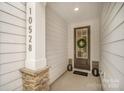 Inviting entryway with stone accents, a stylish front door with a wreath, and a covered porch at 10528 Audubon Ridge Dr, Cornelius, NC 28031