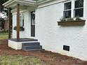 View of front door with planter boxes, gray steps and dark wooden posts, fresh exterior paint at 13131 601 S Hwy, Midland, NC 28107