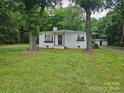 Charming single-story home with white brick, dark door and window boxes nestled among mature trees at 13131 601 S Hwy, Midland, NC 28107
