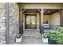 Inviting front porch with stone accents and decorative double doors with a cozy seating area at 15909 Heath Aster Way, Davidson, NC 28036