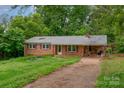 Charming brick ranch-style home featuring a covered carport nestled among lush green trees at 302 Kimberlee Dr, Shelby, NC 28152