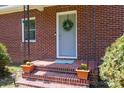 Inviting front porch featuring brick steps, potted flowers, and a wreath on the door of a traditional-style brick home at 311 Airport Rd, Rock Hill, SC 29732