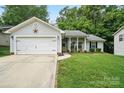 Charming single-story home with a well-manicured lawn, attached garage, and inviting front porch with rocking chairs at 7417 Chidley Dr, Charlotte, NC 28269