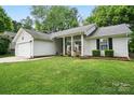Charming single-story home with a well-manicured lawn and an inviting front porch with rocking chairs at 7417 Chidley Dr, Charlotte, NC 28269