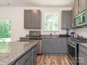 Well-lit kitchen boasts gray cabinetry, stainless steel appliances, granite countertops, and wood-look floors at 11010 Redcoat Hill Ln # 33, Huntersville, NC 28078