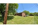 Brick home with a spacious yard, mature trees, and a storage shed at 1684 Montevista Dr, Shelby, NC 28150