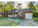 Inviting brick home with an attached garage, covered porch, and a neatly landscaped front yard under sunny skies at 221 Delview Dr, Cherryville, NC 28021