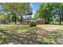 Brick home with a fenced yard, mature trees, and a partially shaded lawn at 4734 Polk Ford Rd, Stanfield, NC 28163