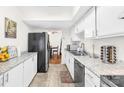 Galley kitchen features white cabinets, granite countertops, stainless steel dishwasher, and dining area access at 7407 Mystic Ln, Charlotte, NC 28227