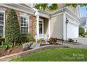 Inviting entrance with stone accents, decorative shutters, bench, and lush landscaping at 10314 Threatt Woods Dr, Charlotte, NC 28277